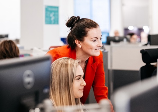 Manager overseeing colleague's work on computer