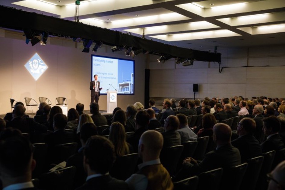 Director presenting on stage at a conference