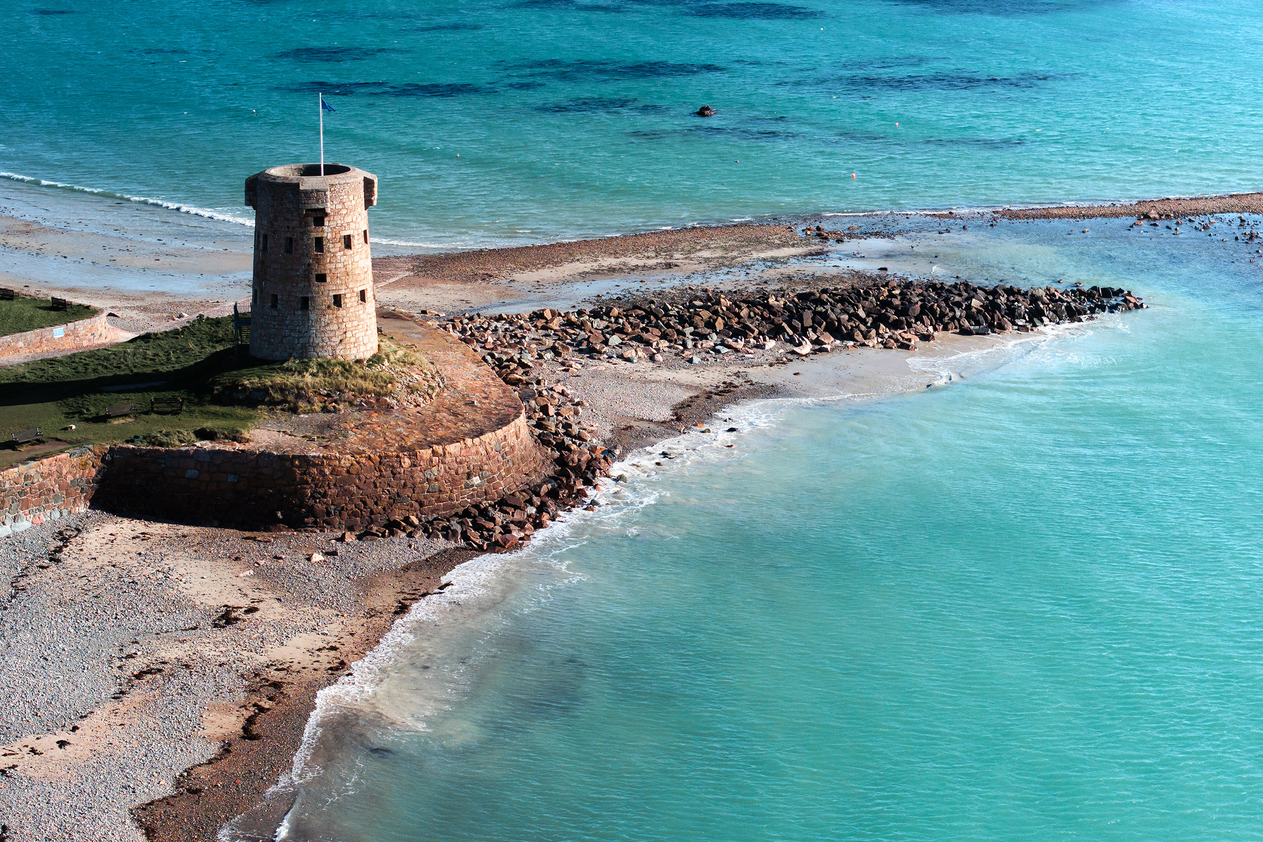 sea and coastal turret in jersey with stones and greenery