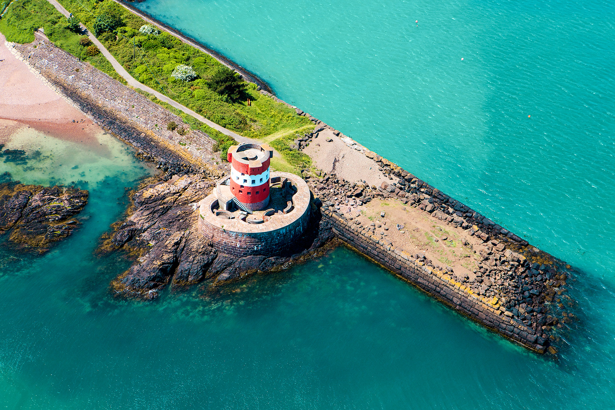jersey coast with vibrant blue sea and green landscape and rocks and pier