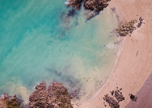 Rocky bay of jersey with waves and sand.